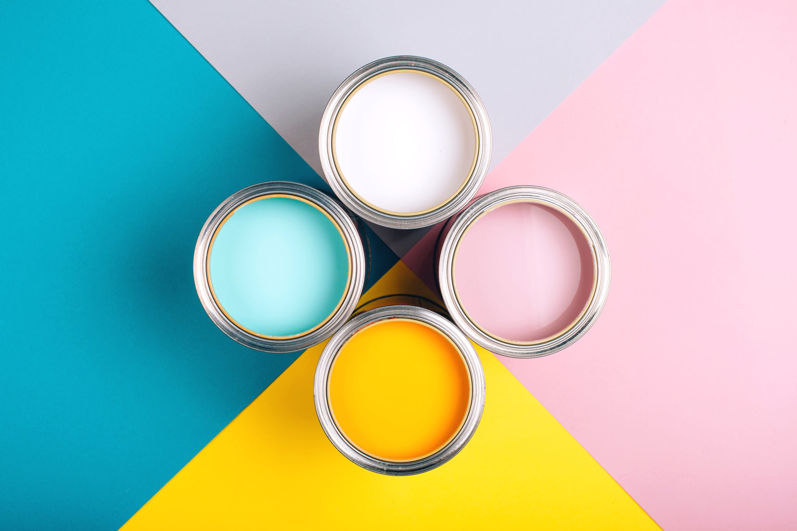 Four open cans of paint on bright symmetry background. Yellow, white, pink, turquoise colors of paint. Place for text. Renovation concept.