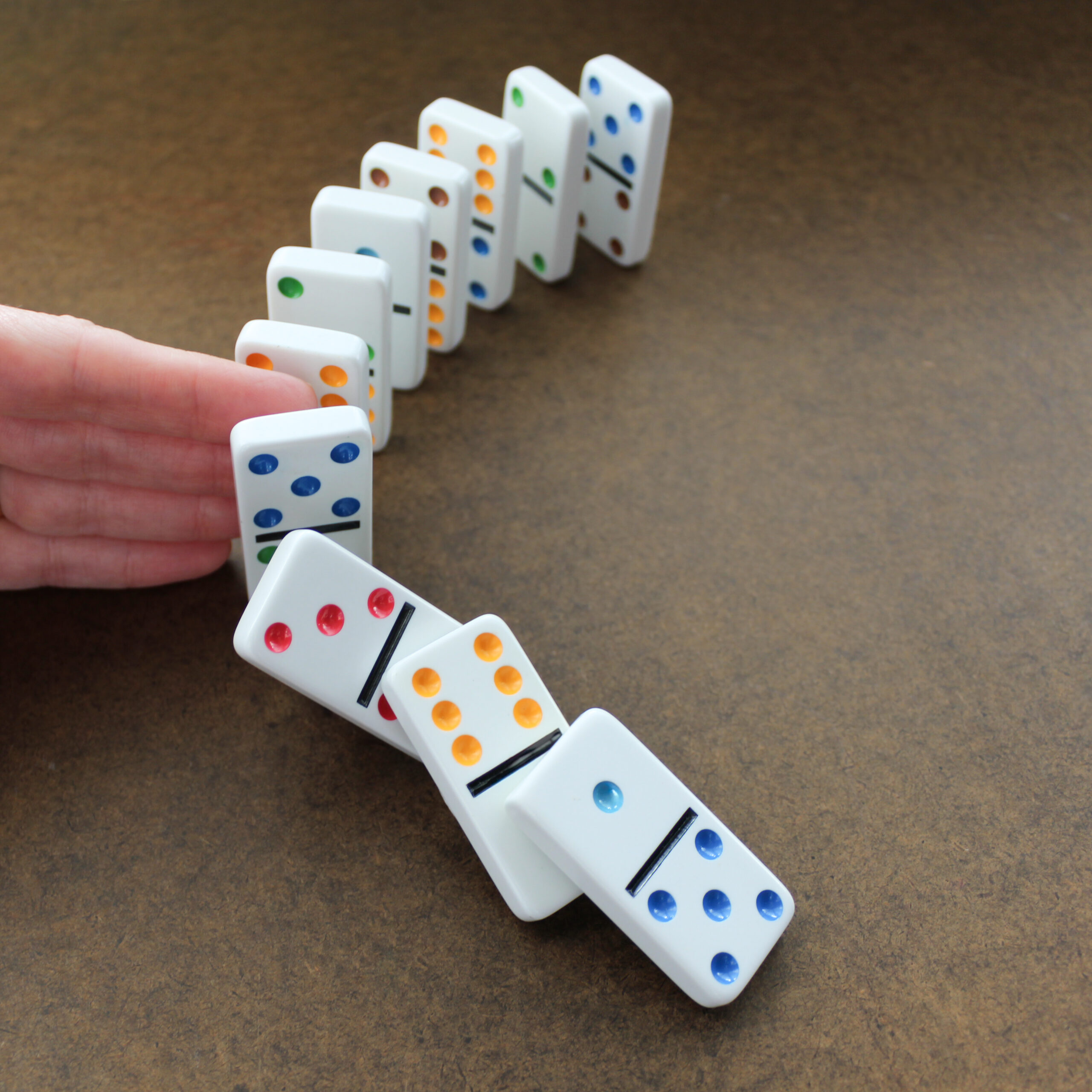 person stopping dominoes with hand finger from falling probability chance future chance metaphor planning games backdrop