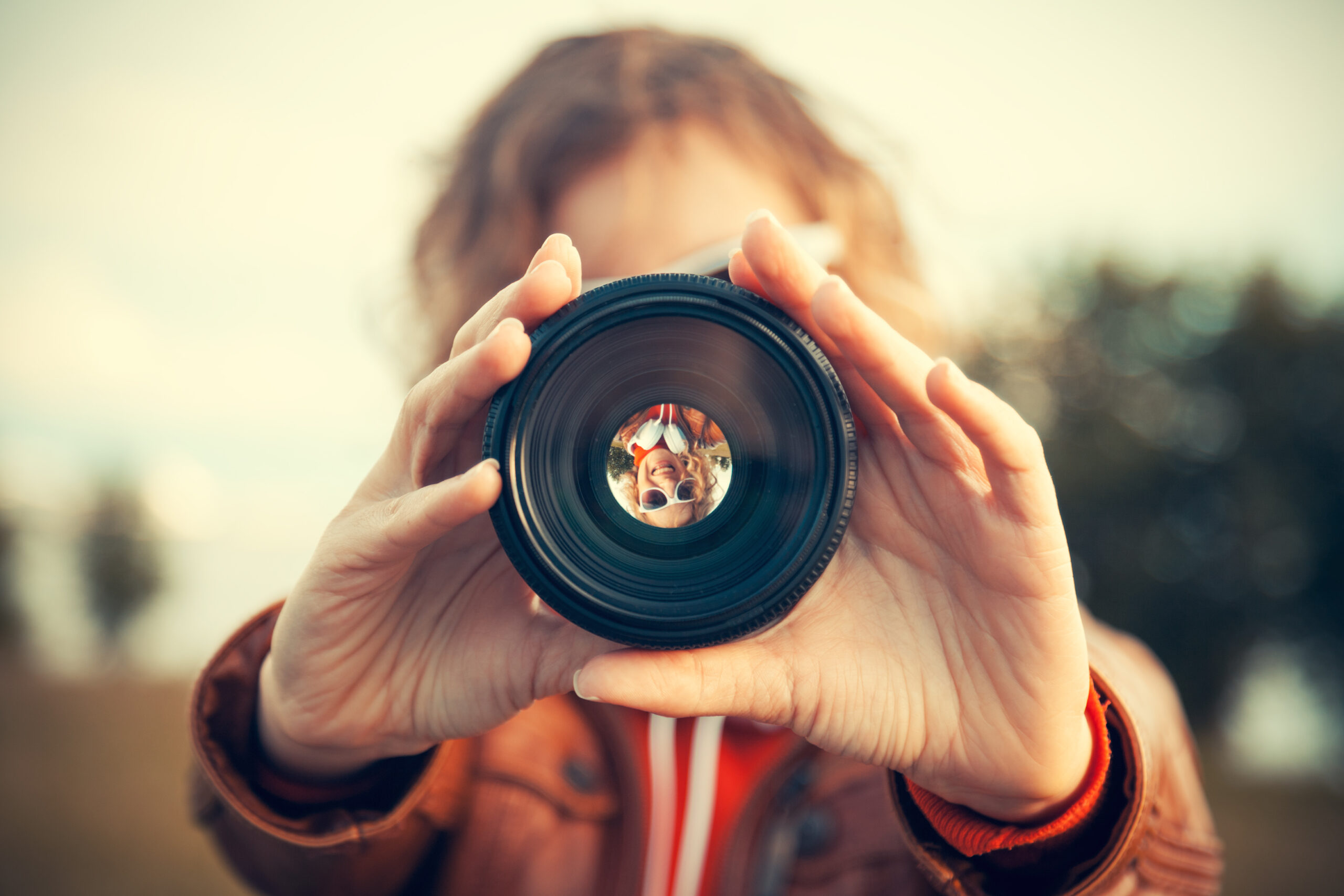 Young woman looking through camera lens