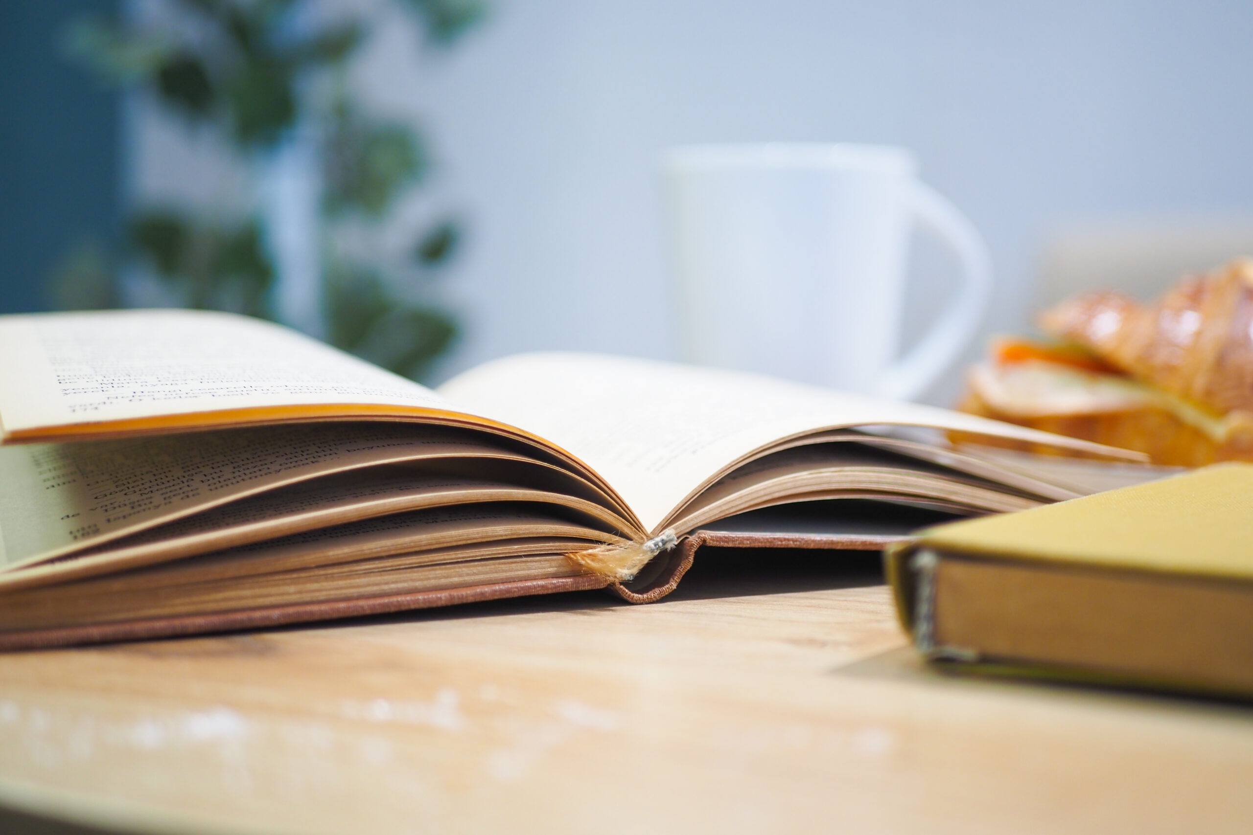 An open book with pages turning on a wooden table set against a green background