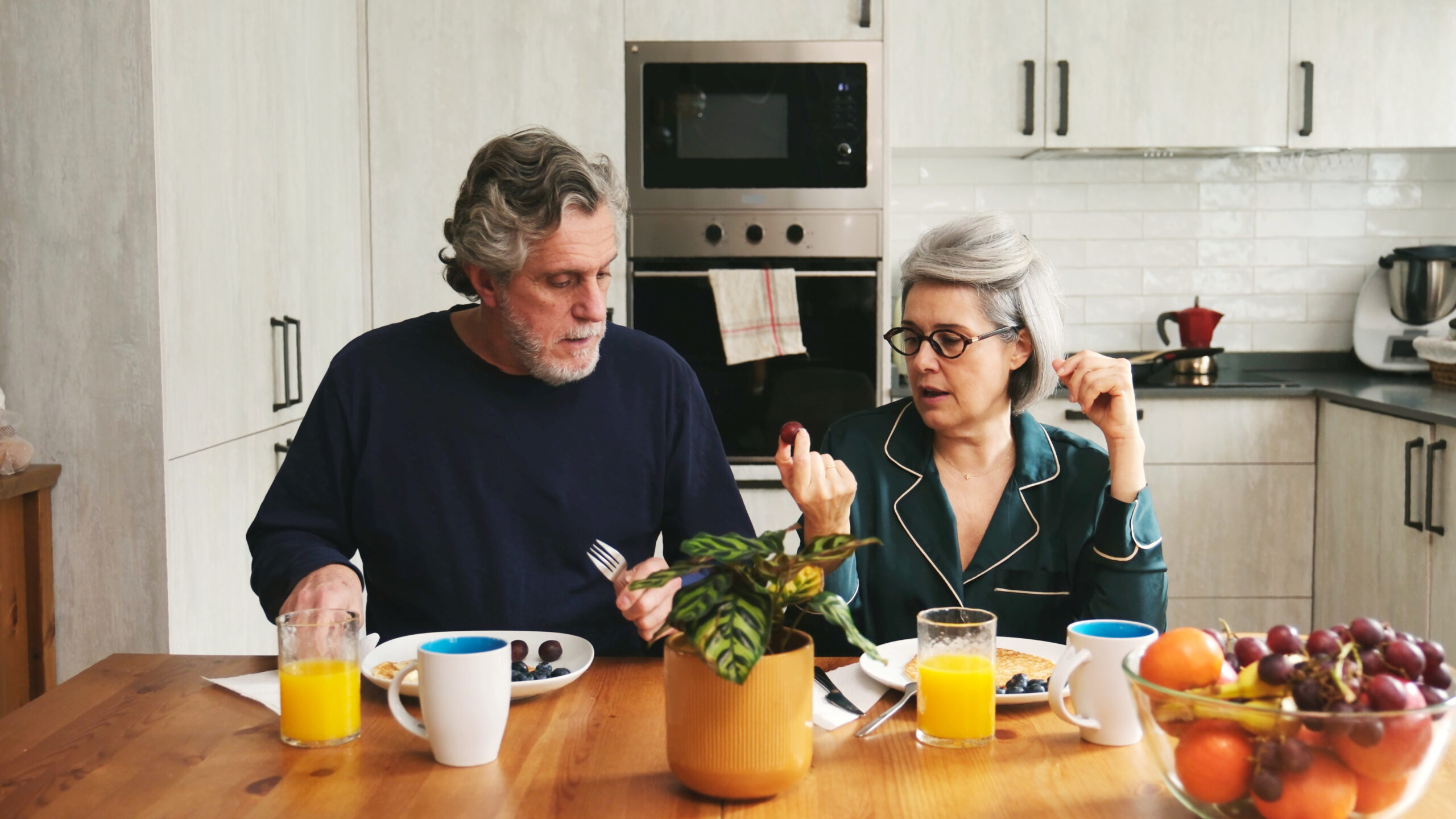 Senior couple having a leisurely breakfast together while talking in their kitchen