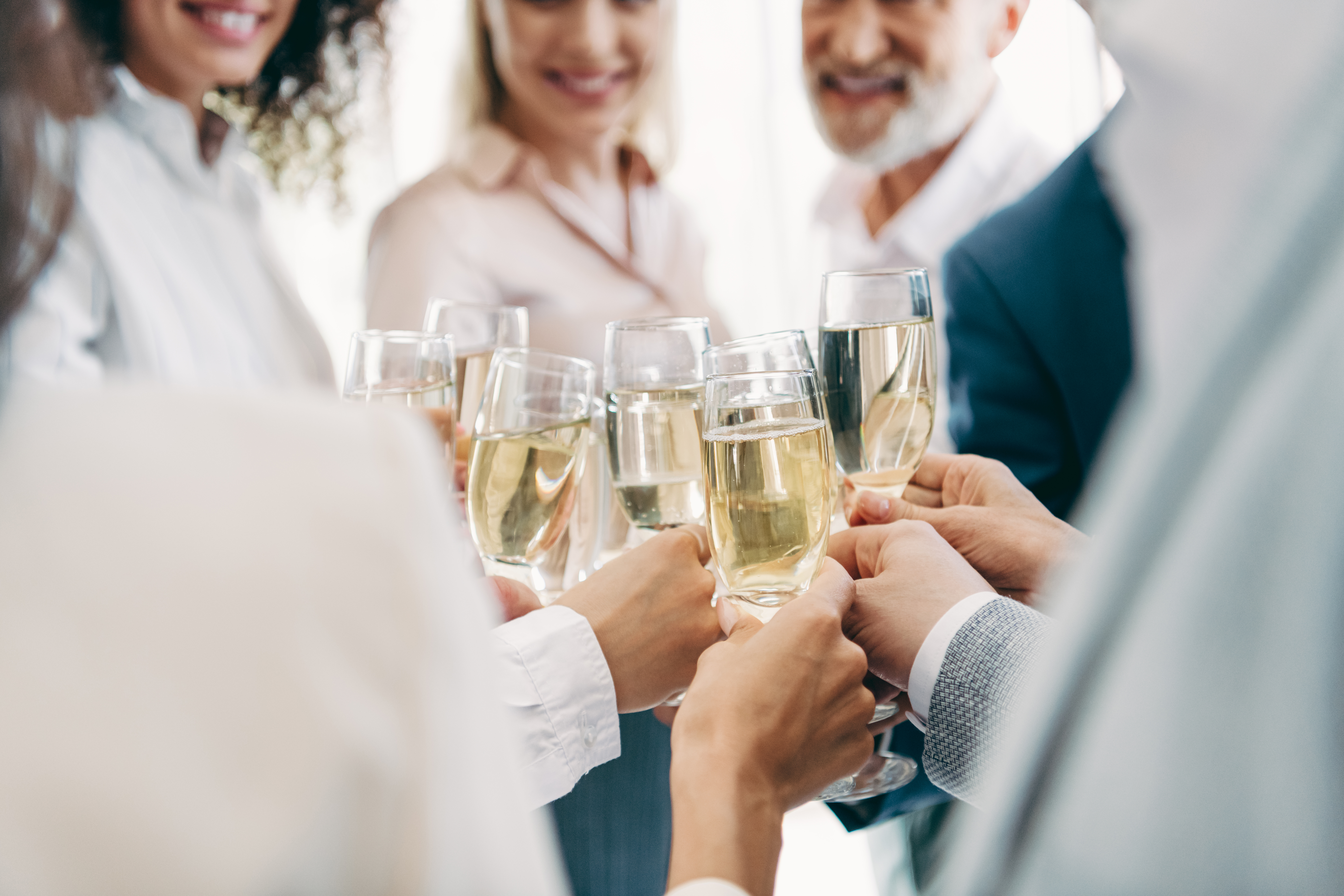 Gathering of diverse professionals raising glasses in a cheerful toast, celebrating success and teamwork in a stylish corporate setting.