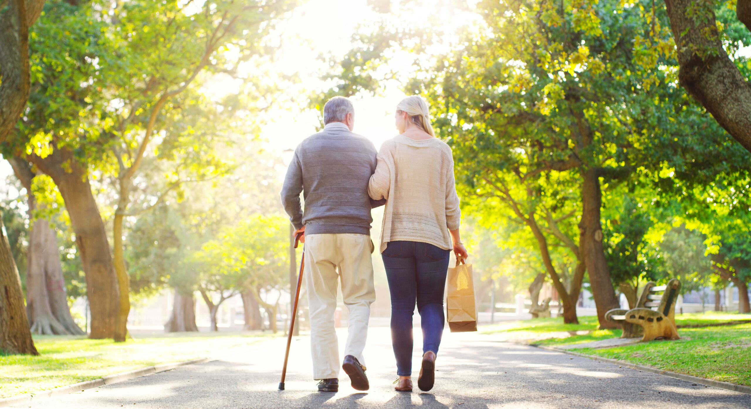 Back, woman and senior father in a park, walking and care with fresh air, bonding and loving together. Family, male parent and female adult outdoor, street and peace with routine, wellness and break.